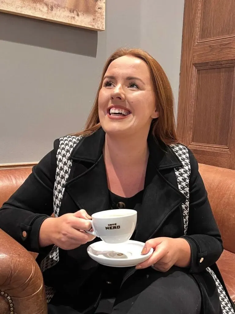 chloe sitting on a sofa in caffe nero holding a free coffee