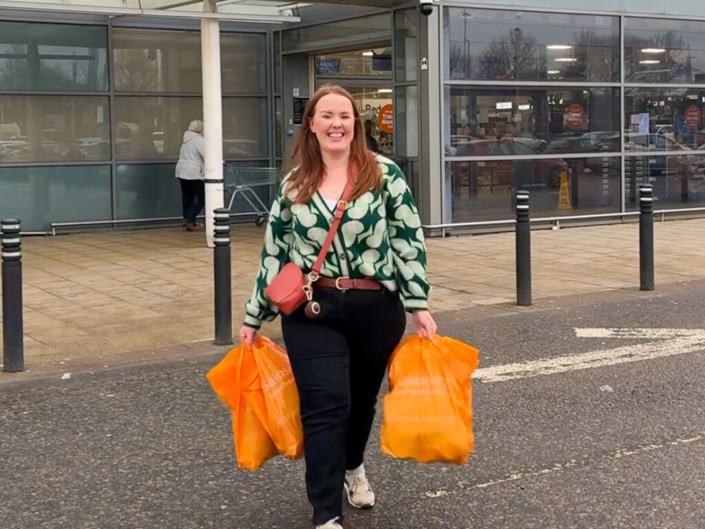 Chloe of Chloe's Deal Club walking out of a supermarket carrying bags after paying for her shopping with the everup cashback app