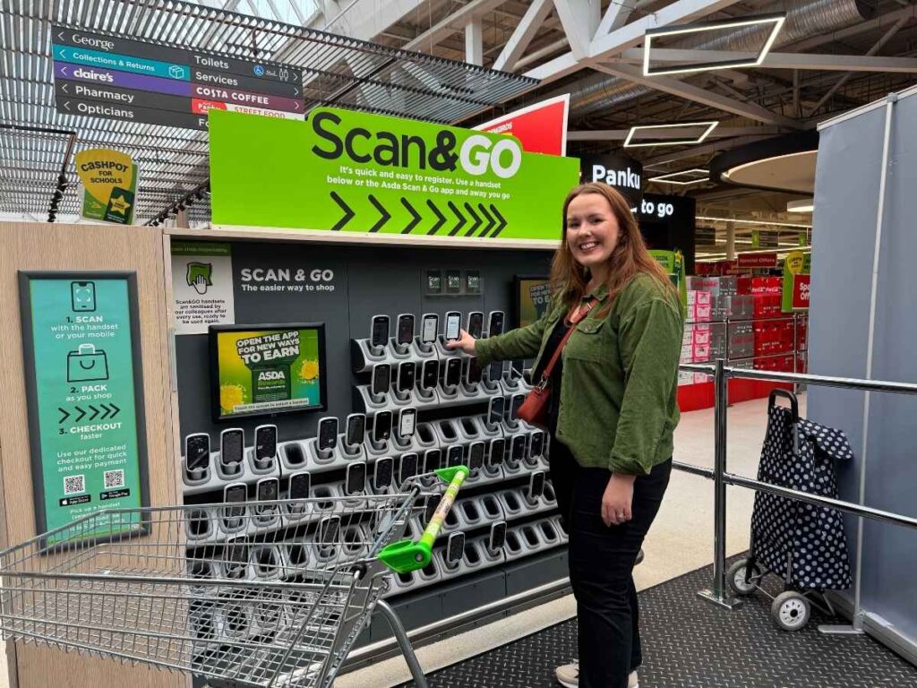 Chloe from Chloe's deal club standing next to the Asda Scan & Go in-store to save money at Asda