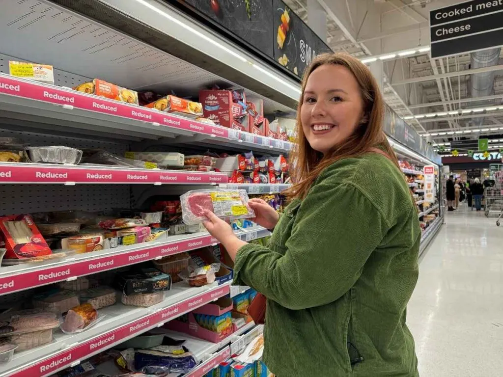 Chloe holding an in-store reduction in Asda supermarket with yellow sticker showing how to save money at Asda