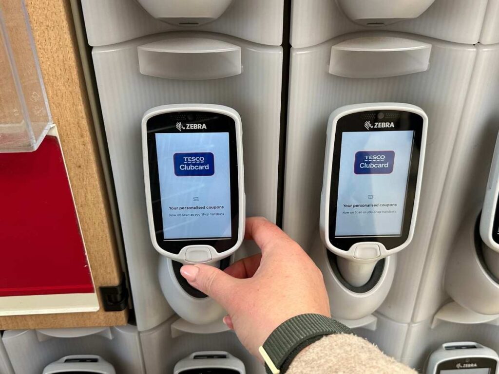 Chloe's hand holding a scan as you shop scanner at Tesco to save money on your shopping