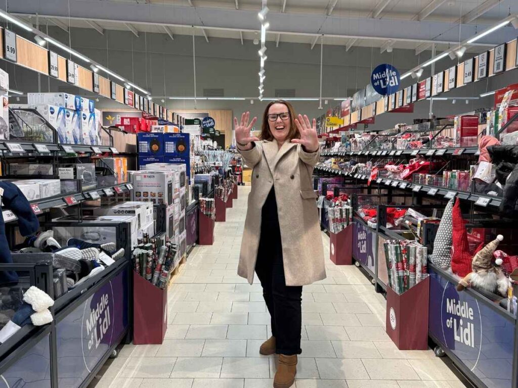 Chloe standing in the middle aisle of Lidl.  A great place to save money