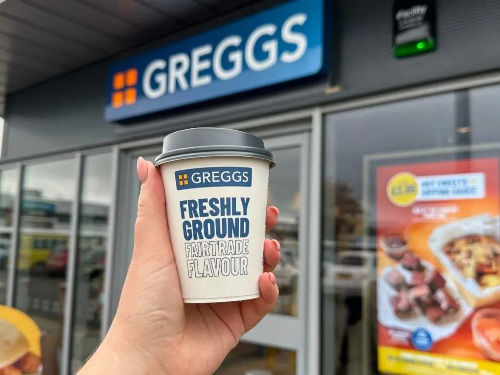 A hand holding a Greggs coffee cup to show to get a free coffee at Greggs