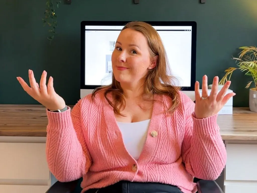 chloe carmichael of chloe's deal club sitting at her desk shrugging her shoulders